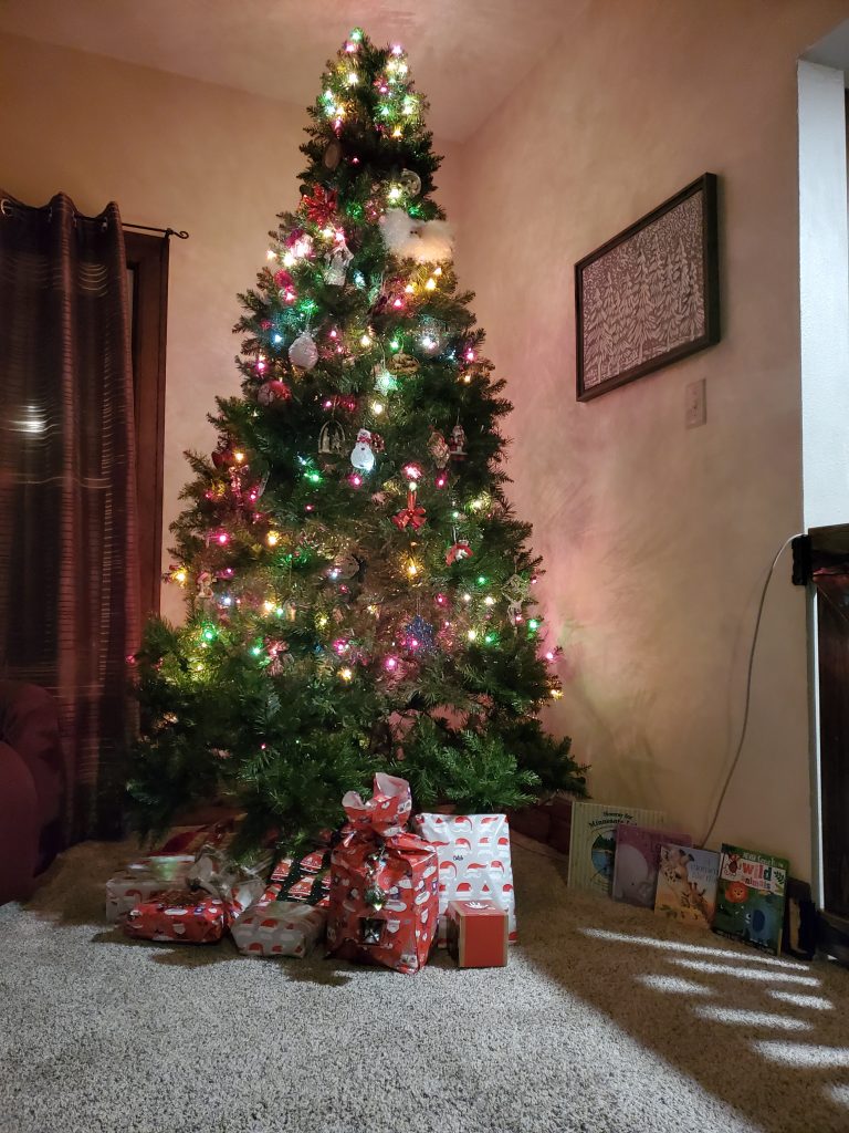 Multicolored Christmas trees with gifts and books underneath. 