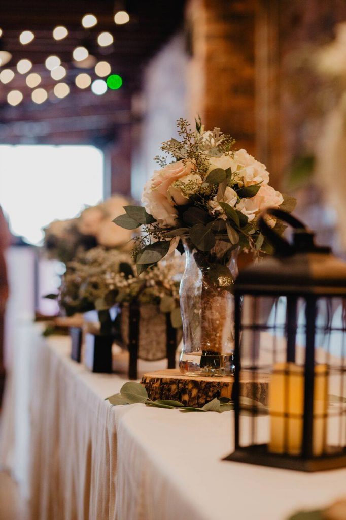 Wedding decorations on a table with white table cloth with black lantern and flowers. 