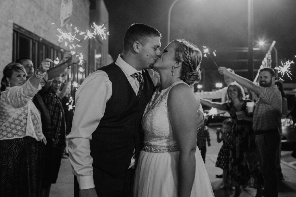 Sparklers in the background of a black and white picture of a groom on the left and bride on the right