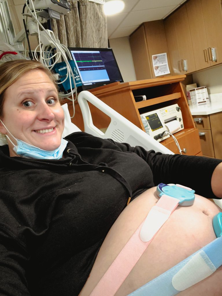 Pregnant woman wearing a black sweatshirt with a belly monitor on